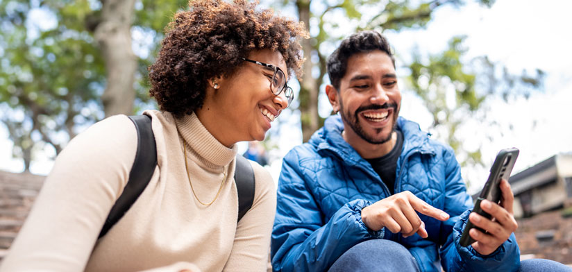 Happy couple outdoors using a smartphone mobile device, Why Travis Credit Union