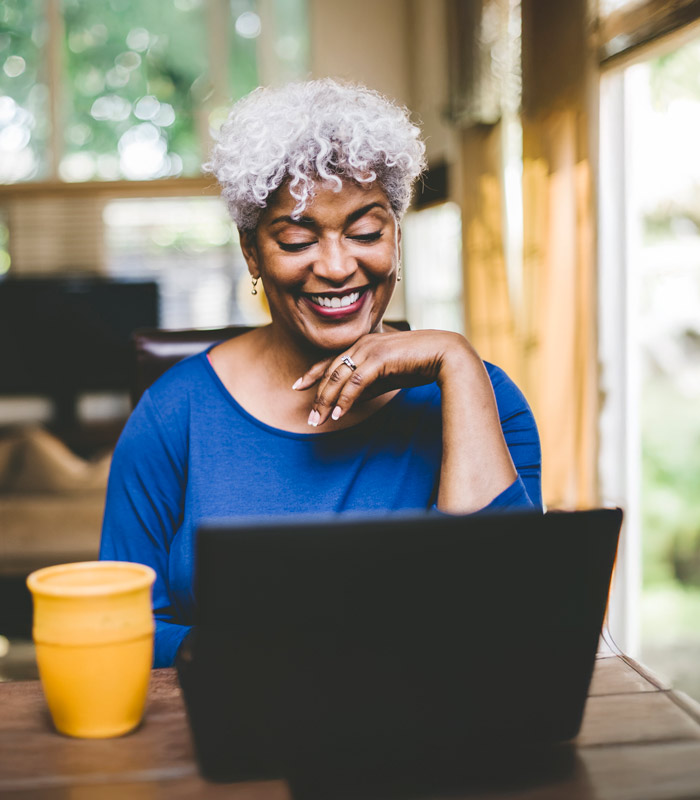 smiling woman at table with coffee and laptop computer